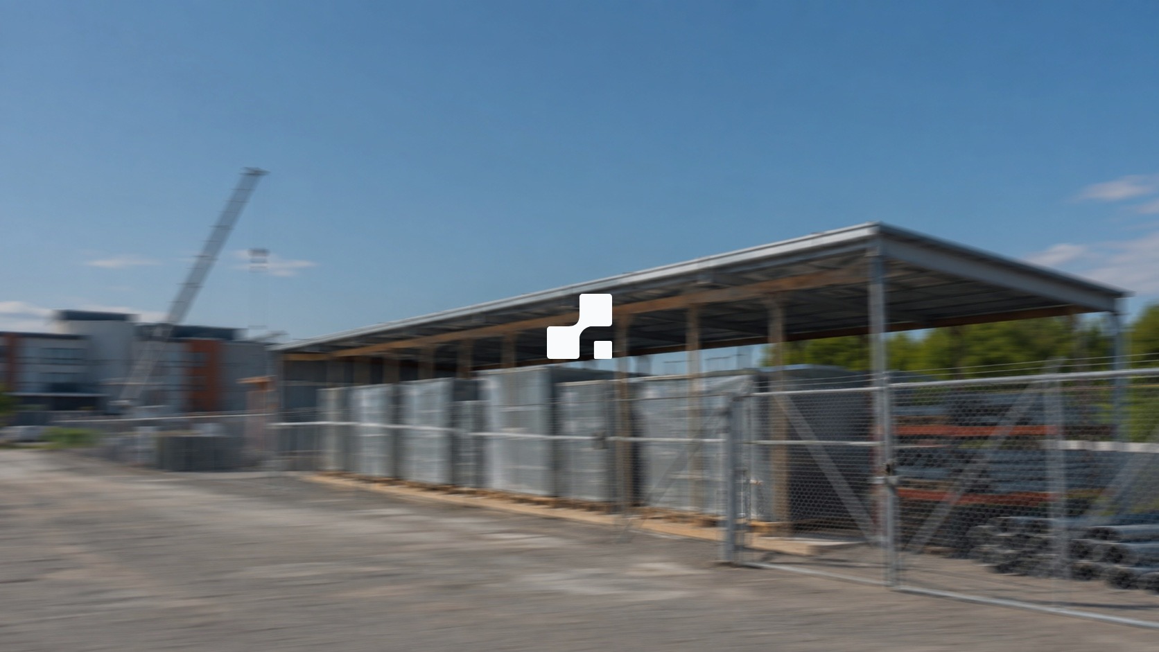 Vue estivale en flou de mouvement de matériaux électriques protégés près d’un chantier institutionnel canadien, sur laquelle figure le symbole Aplon