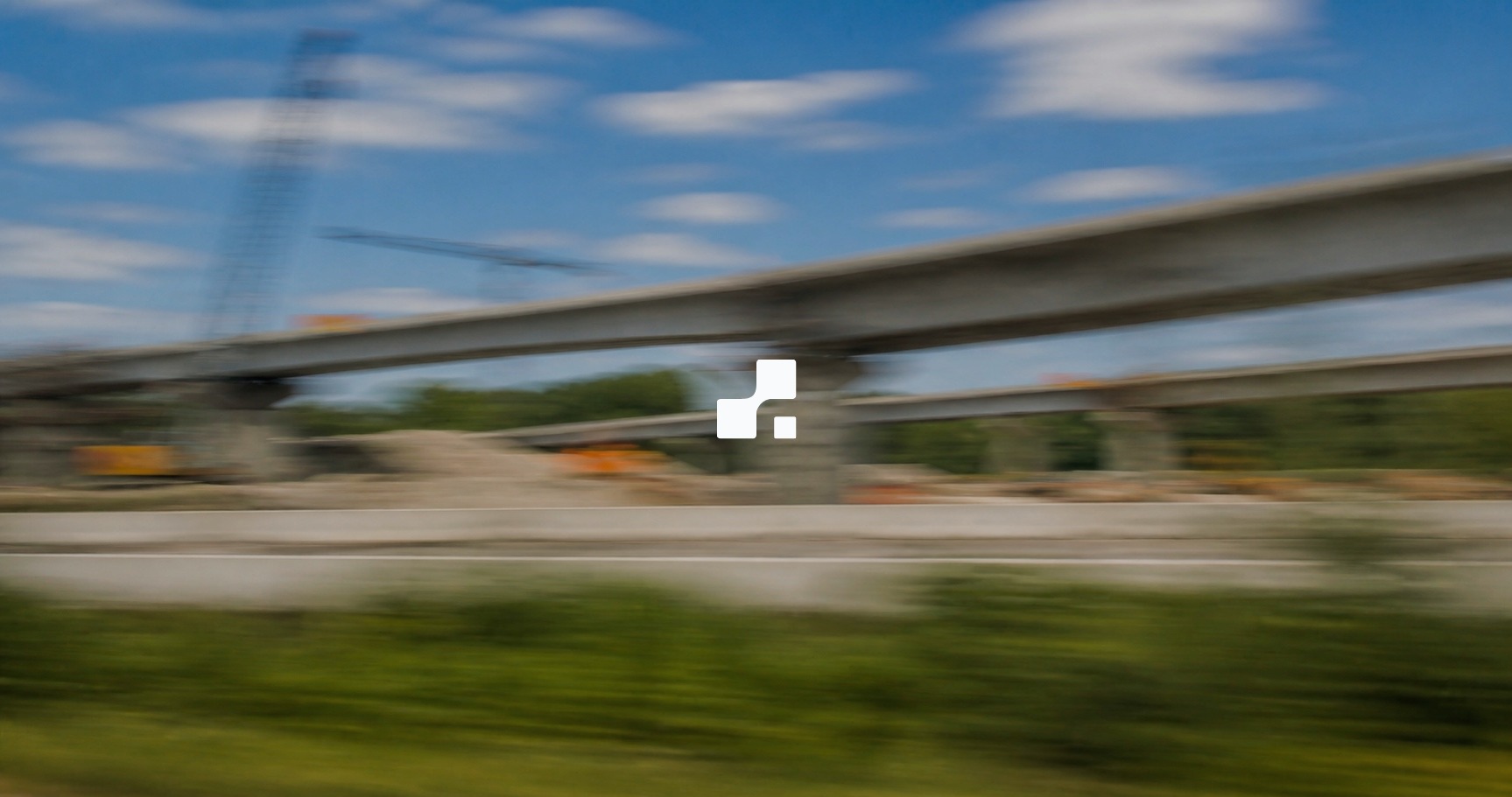 Vue estivale floutée par le mouvement d’un échangeur autoroutier en construction, sur laquelle figure le symbole Aplon
